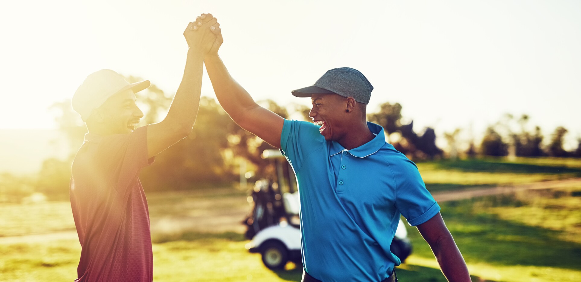 twosome golfers celebrate with high five on golf course with sunshine