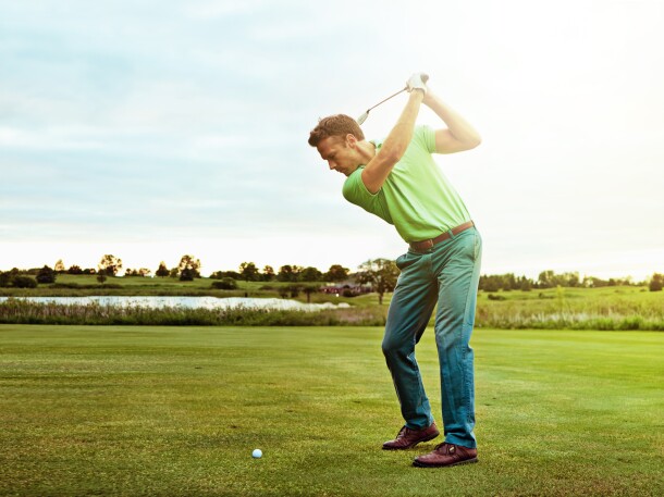 golfer swinging club on golf course